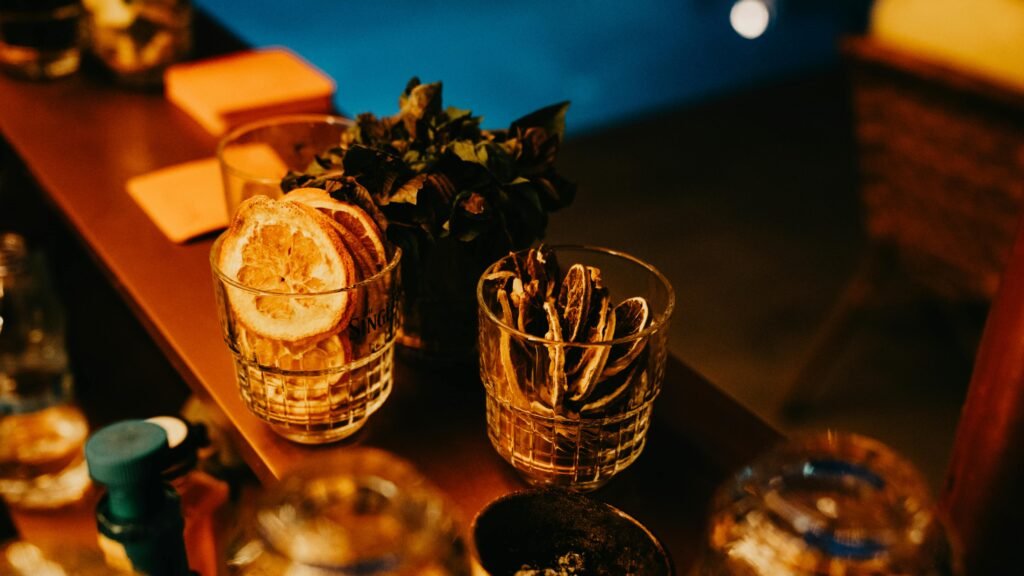 A stylish bar counter with dried citrus slices and herbs under warm lighting.