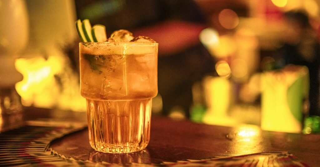 Close-up of a cocktail glass with bright bokeh background in a cozy bar setting.